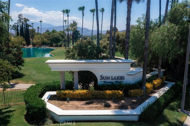 community / neighborhood sign with a lawn, a mountain view, and fence