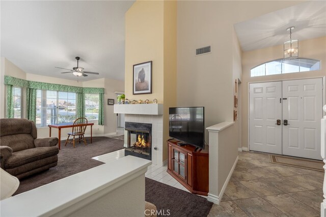 foyer featuring baseboards, a fireplace, visible vents, and high vaulted ceiling