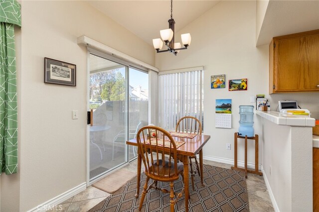 dining space featuring lofted ceiling, a notable chandelier, baseboards, and light tile patterned floors