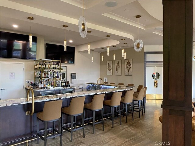 bar featuring hanging light fixtures, wet bar, and a tray ceiling