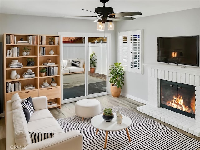 living room with light wood finished floors, a fireplace, baseboards, and a wealth of natural light