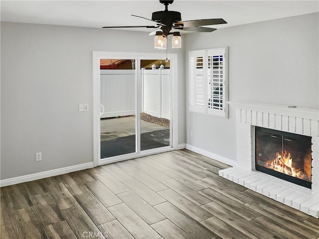 unfurnished living room with ceiling fan, a fireplace, wood finished floors, and baseboards