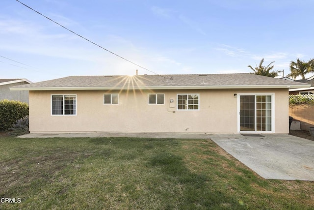 back of property featuring a shingled roof, a patio area, a yard, and stucco siding