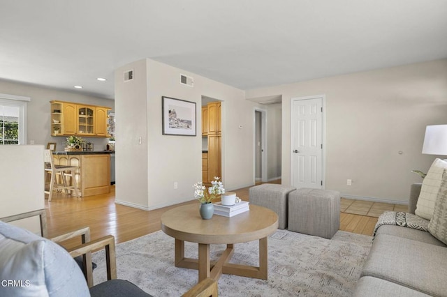 living area with light wood finished floors, visible vents, and baseboards