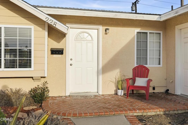 entrance to property featuring a patio area and stucco siding