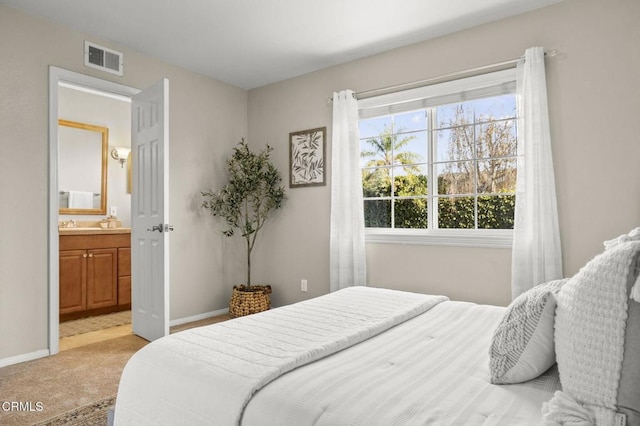 bedroom with light carpet, connected bathroom, visible vents, and baseboards