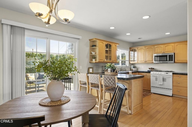 kitchen featuring decorative light fixtures, stainless steel microwave, gas range gas stove, dark countertops, and glass insert cabinets