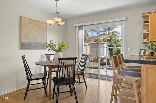 dining room featuring light wood-style floors, baseboards, and a chandelier