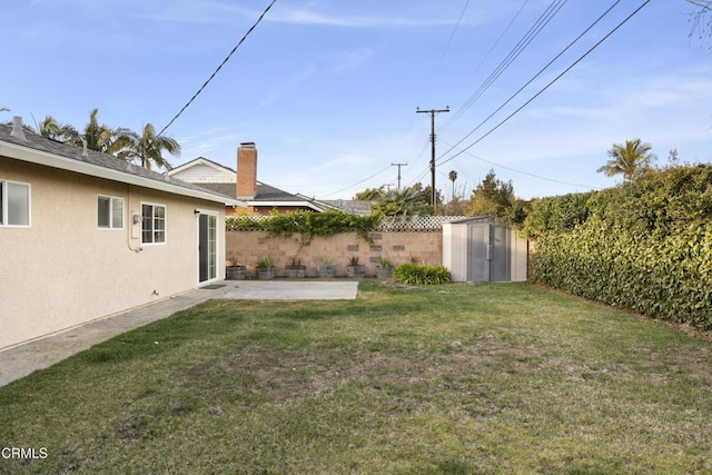 view of yard with a fenced backyard, a patio, an outdoor structure, and a shed