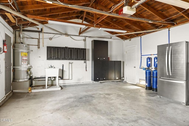 garage featuring water heater, a garage door opener, a sink, and freestanding refrigerator