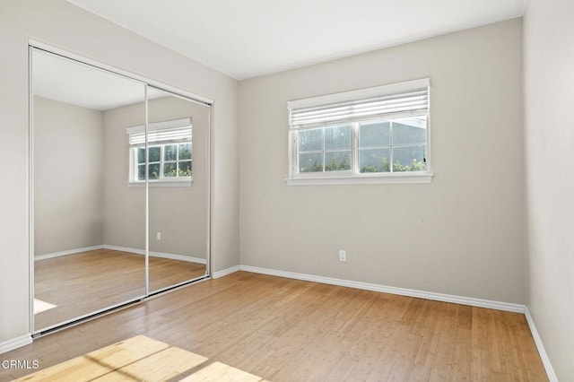 unfurnished bedroom featuring a closet, baseboards, and wood finished floors