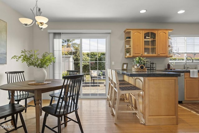 kitchen featuring dark countertops, glass insert cabinets, hanging light fixtures, light wood-style floors, and open shelves