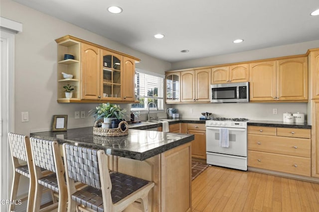 kitchen with white range with gas stovetop, stainless steel microwave, a peninsula, and open shelves