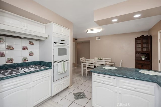 kitchen featuring white appliances, white cabinets, decorative backsplash, and light tile patterned floors