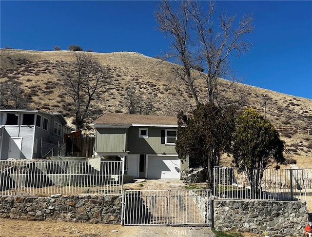 view of front of property featuring driveway, a garage, fence, and a mountain view