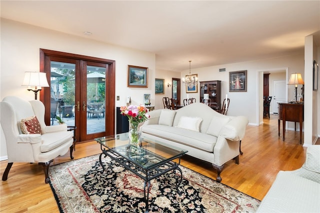 living room featuring hardwood / wood-style flooring, a chandelier, and french doors