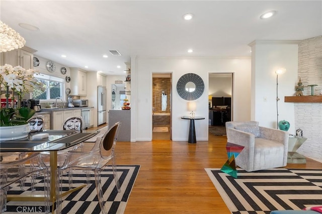 interior space with light hardwood / wood-style flooring, crown molding, a fireplace, and sink