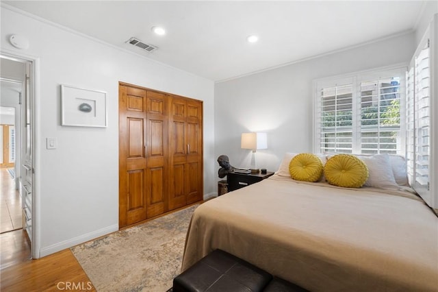 bedroom with a closet, wood-type flooring, and ornamental molding