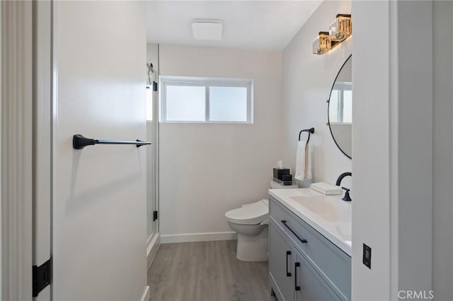 bathroom featuring toilet, vanity, wood-type flooring, and a healthy amount of sunlight