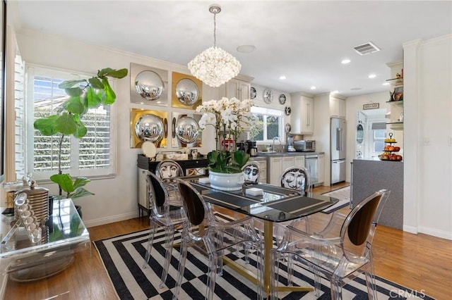 dining space featuring an inviting chandelier, light hardwood / wood-style flooring, and sink