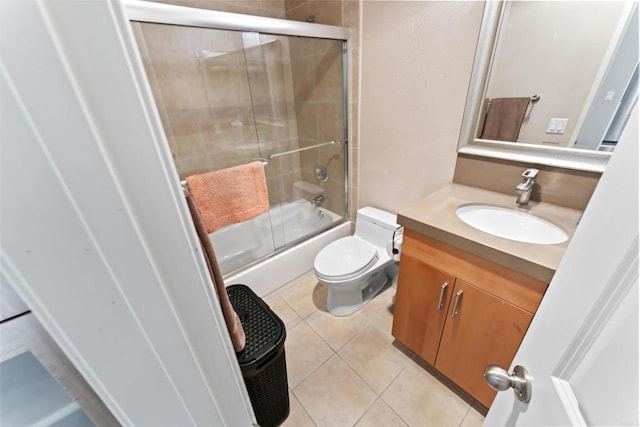 bathroom featuring enclosed tub / shower combo, toilet, vanity, and tile patterned floors