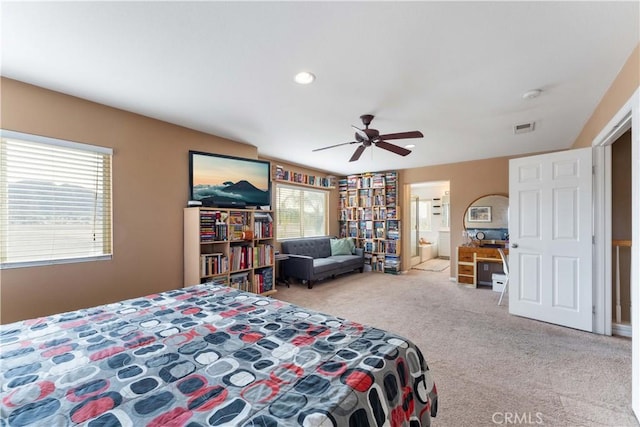 carpeted bedroom with ceiling fan, multiple windows, and ensuite bathroom