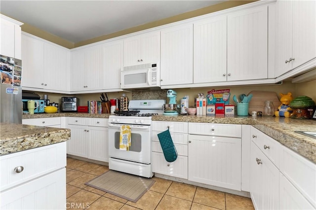 kitchen with white cabinetry, white appliances, and light tile patterned floors