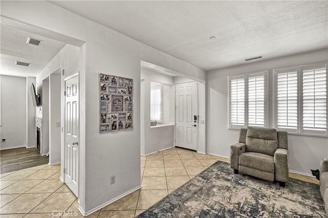 entrance foyer with baseboards, visible vents, a textured ceiling, and light tile patterned flooring