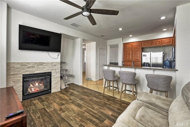 living room with a fireplace, light hardwood / wood-style flooring, and ceiling fan