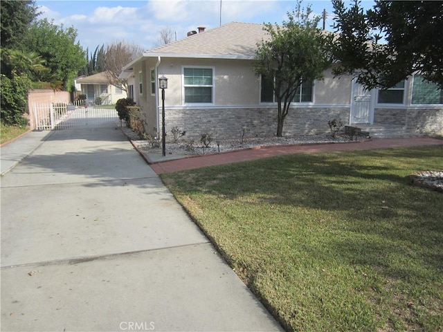 view of side of property featuring driveway, stone siding, a lawn, and stucco siding