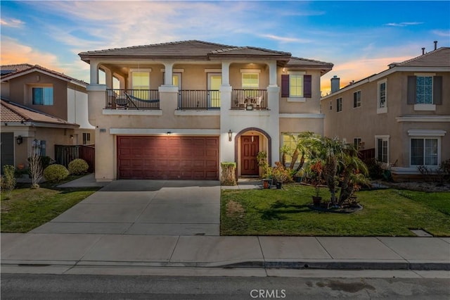 mediterranean / spanish home featuring stucco siding, concrete driveway, a lawn, a balcony, and a garage