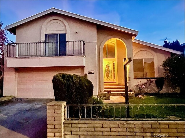 view of front of property with stucco siding, a balcony, a garage, and driveway