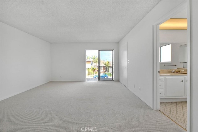 empty room with light colored carpet and a textured ceiling