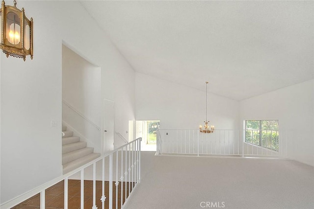 hall with an inviting chandelier, carpet flooring, and high vaulted ceiling