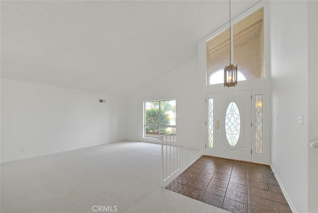 foyer entrance featuring visible vents, high vaulted ceiling, and carpet flooring