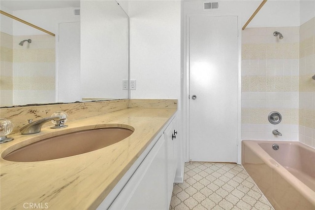 bathroom with visible vents, vanity, and shower / tub combination