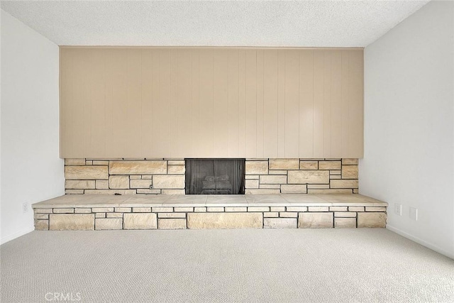 unfurnished living room with a stone fireplace, carpet, and a textured ceiling