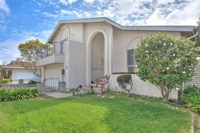 view of front of property featuring stucco siding, a balcony, a garage, and a front lawn