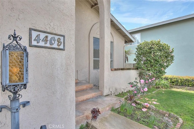 property entrance with stucco siding and a yard