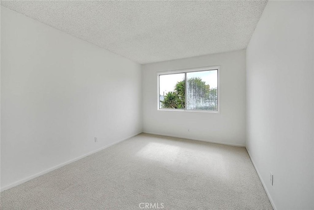 spare room featuring baseboards, a textured ceiling, and carpet flooring