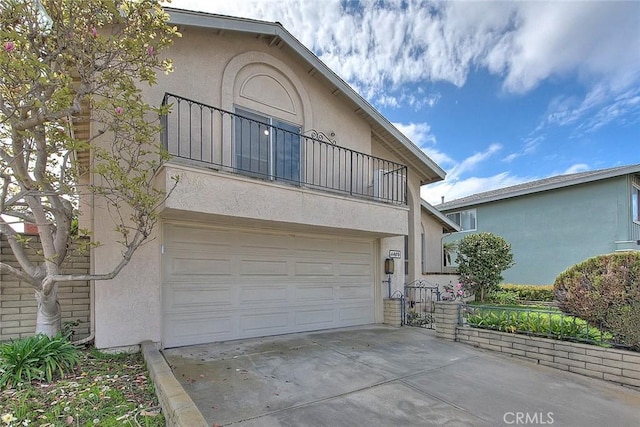 view of front of home featuring a balcony, stucco siding, driveway, and a garage