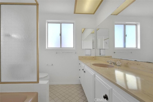 bathroom featuring baseboards, toilet, a bath, washer / clothes dryer, and vanity