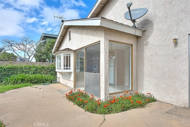 view of home's exterior with a patio, fence, and stucco siding