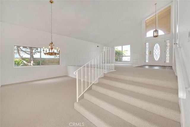 foyer entrance featuring a notable chandelier, stairway, carpet flooring, and high vaulted ceiling