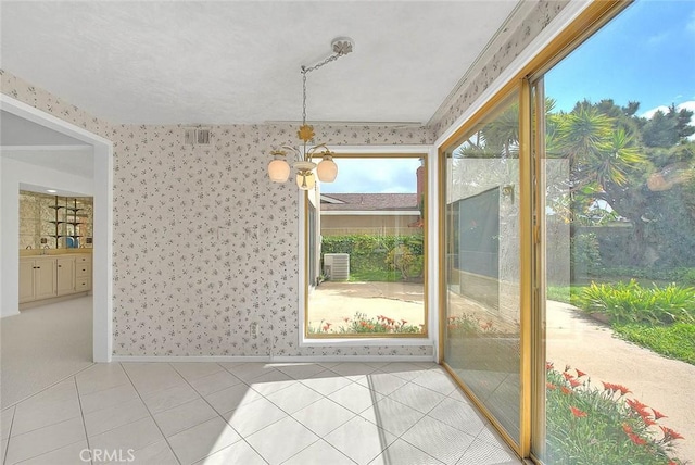 unfurnished dining area featuring light tile patterned floors, a notable chandelier, wallpapered walls, and baseboards