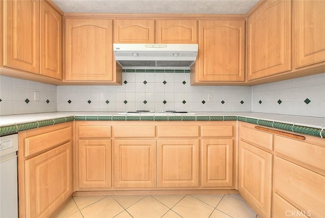 kitchen with under cabinet range hood, light brown cabinetry, white appliances, and tile countertops