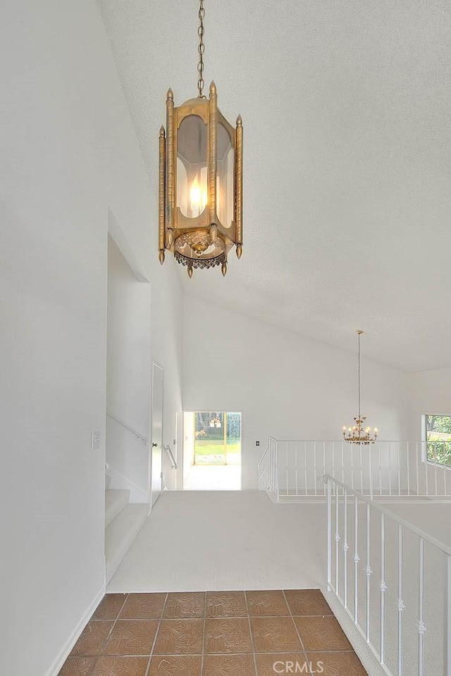 empty room featuring a textured ceiling, a notable chandelier, and high vaulted ceiling