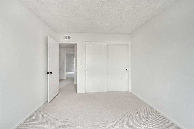 unfurnished bedroom featuring visible vents, baseboards, carpet flooring, a closet, and a textured ceiling