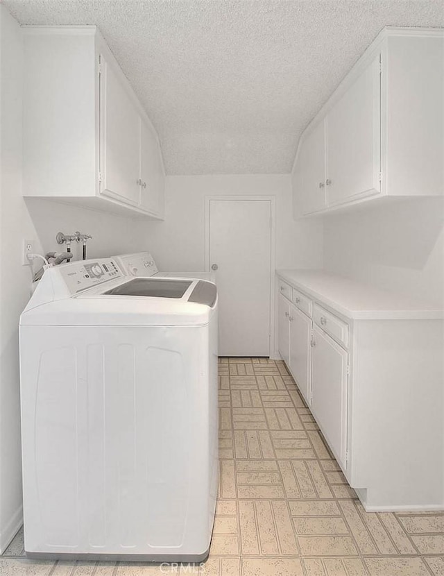 laundry room with washer and clothes dryer, cabinet space, and a textured ceiling