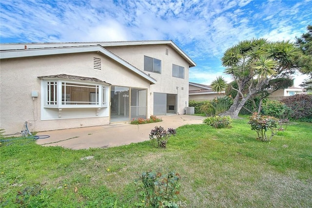 back of property with a patio, a lawn, and stucco siding